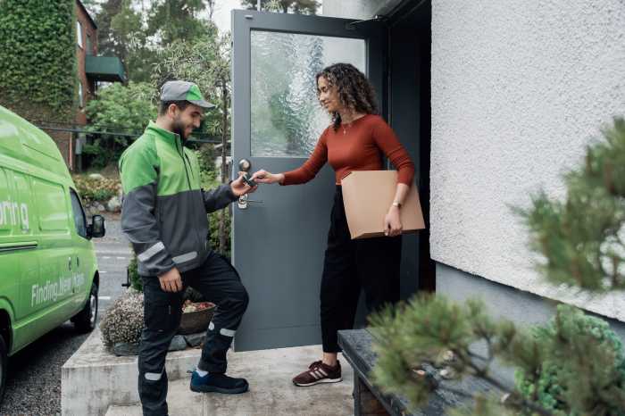 Ett Bringbud levererar ett paket till dörren hos en kvinna som signerar för leveransen på en telefon