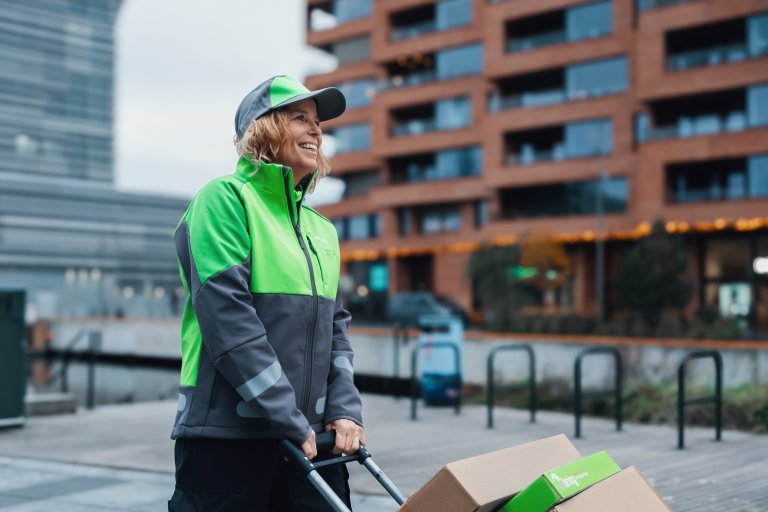 Ett kvinnligt Bringbud drar en pirra med paket på genom staden