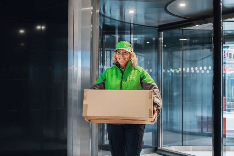 Ett Bringbud går in genom en snurrande dörr och bär på ett stort paket