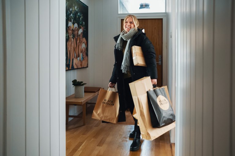 En kvinna går i hallen med en massa påsar i händerna som det står Black Friday på
