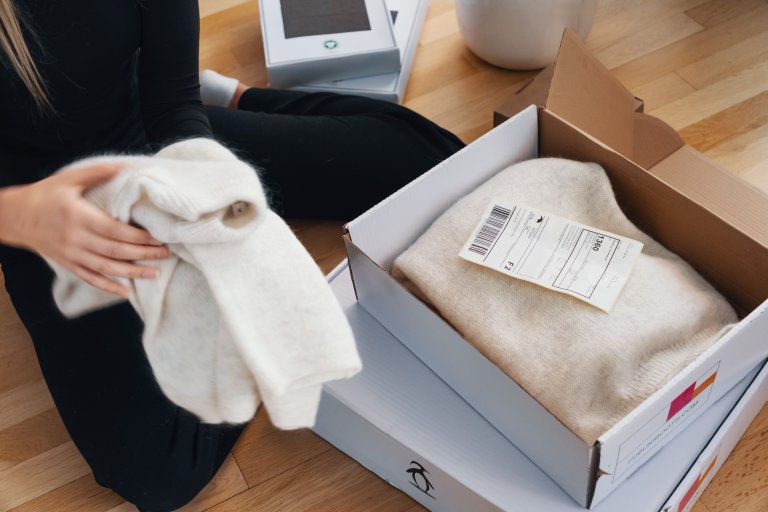 En kvinna sitter framför ett paket som hon förbereder för en retur
