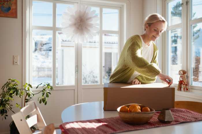 En kvinna står med ett paket på ett bord framför sig