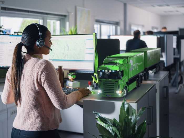 En medarbetare på Bring kundservice står framför en dator med ett headset på huvudet