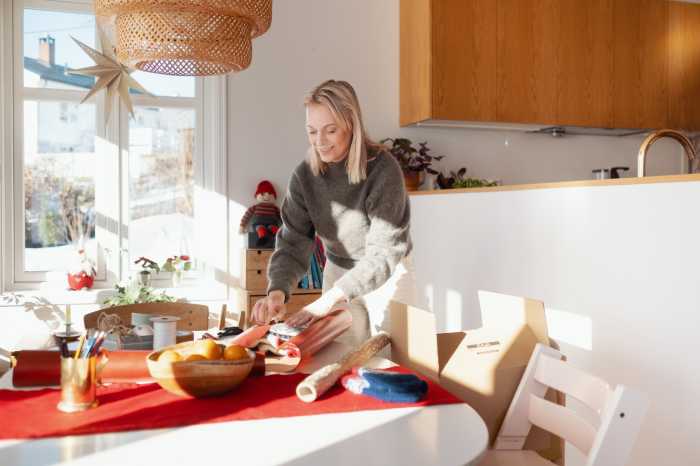 En leende kvinna står lutad över ett bord medan hon slår in en julklapp som hon har handlat på Black Friday