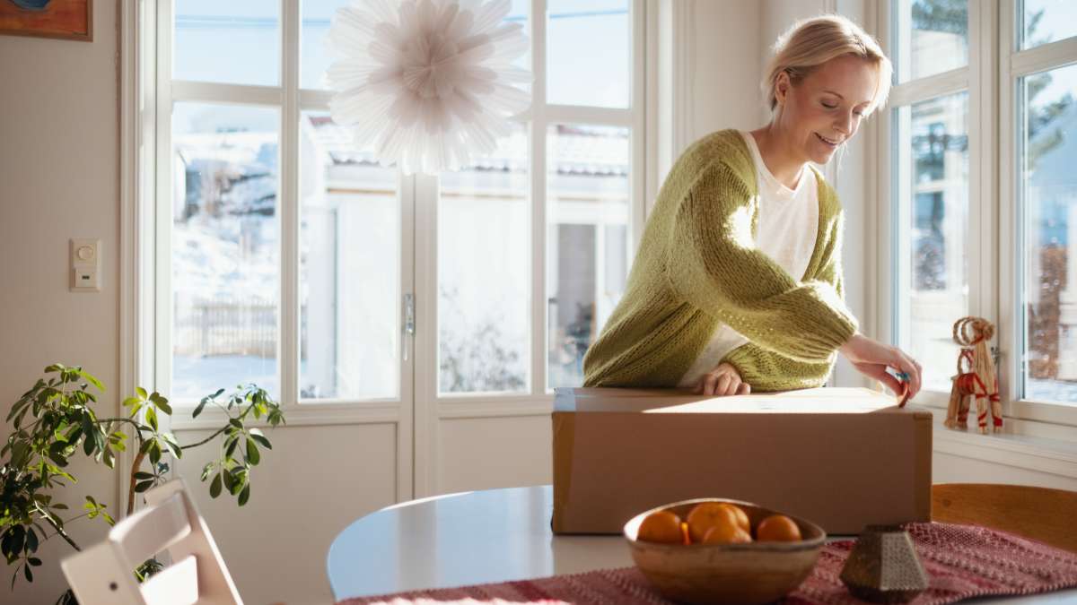 En kvinna står med ett paket på ett bord framför sig