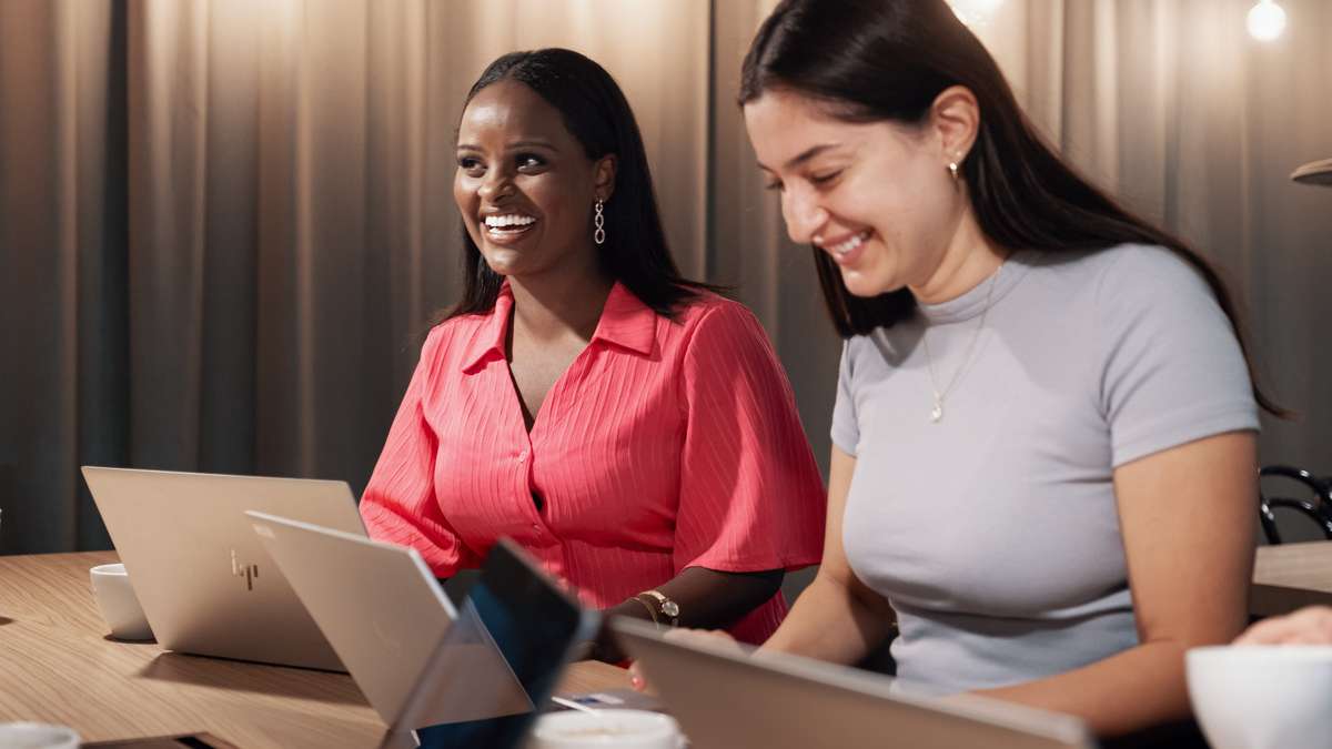 Två kvinnor arbetar på sina datorer.