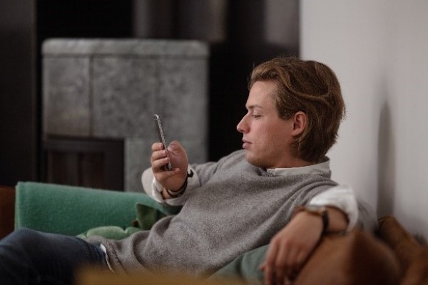 En man sitter och surfar på sin mobiltelefon