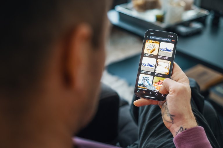 En man sitter med en telefon i handen och ska näthandla från en webbutik