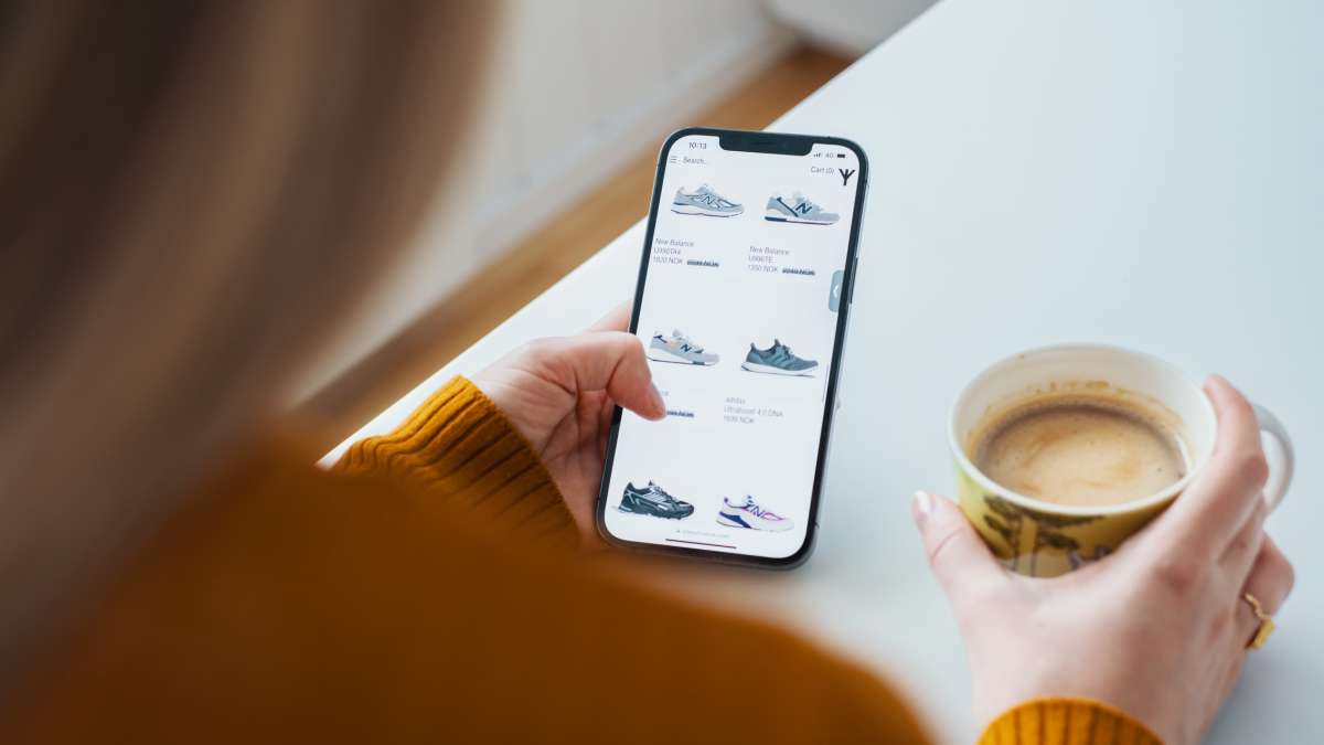 En kvinna har en mobil i handen med en webbutik och ska handla på nätet
