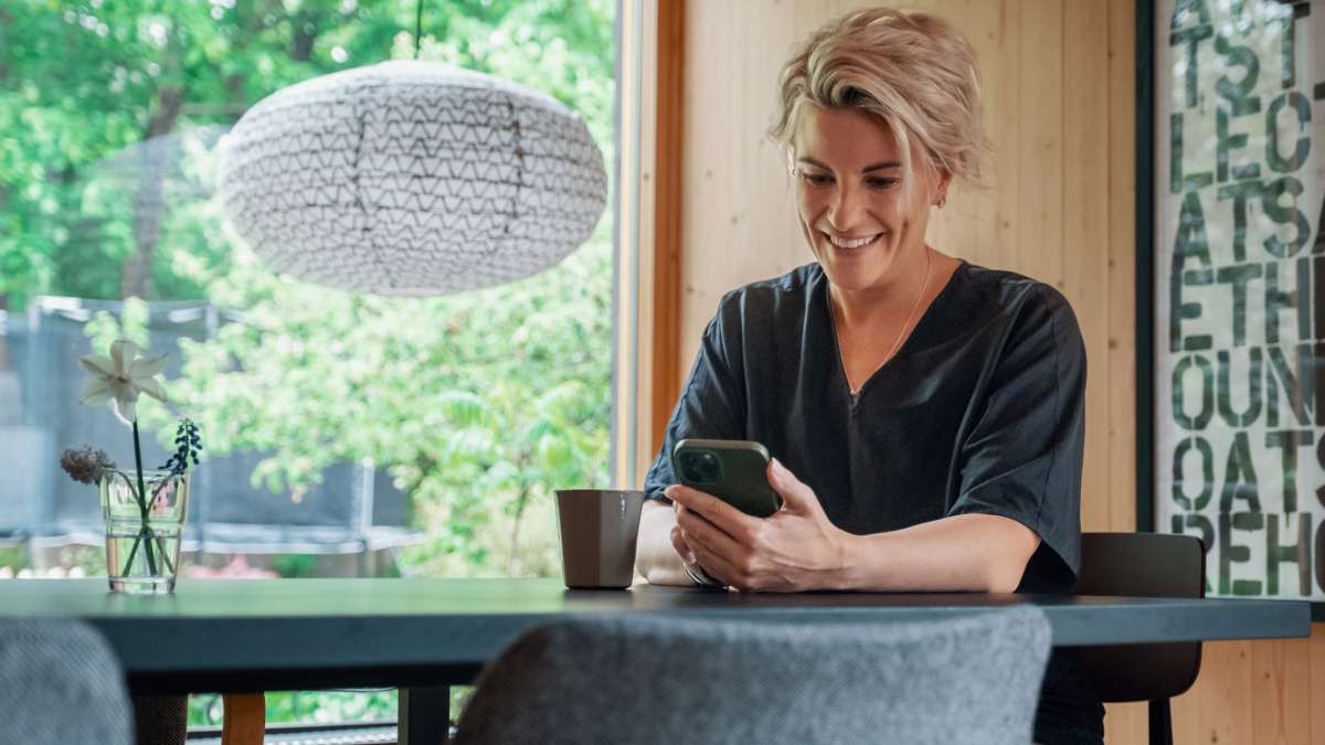 En leende kvinna tittar på sin mobiltelefon