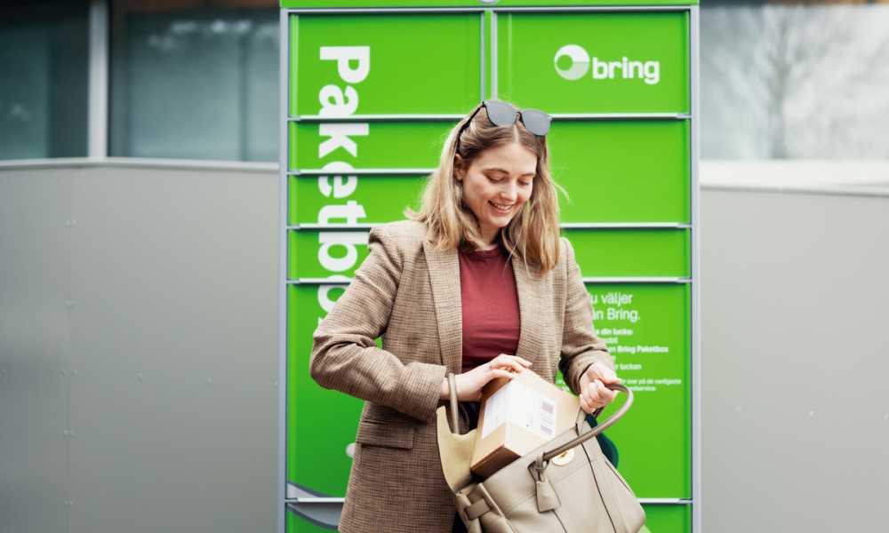 En kvinna står framför en Bring paketbox och stoppar ner ett paket i en ryggsäck.